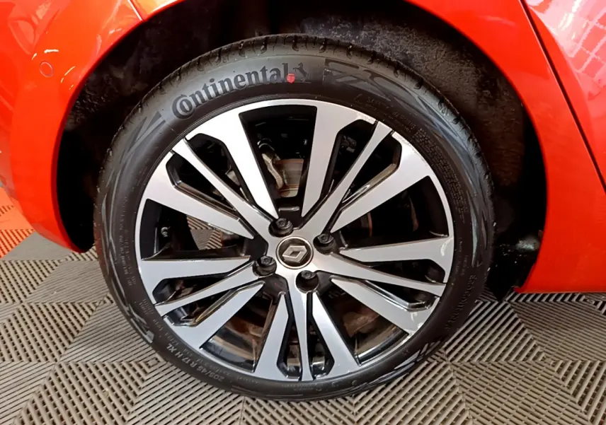 Gros plan sur la roue avant gauche de la Renault Clio orange, mettant en valeur la jante alliage et le pneu Continental.