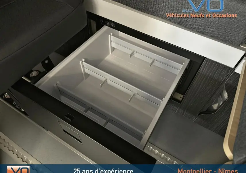 Tiroir de rangement ouvert sous le siège dans l'habitacle du Renault Trafic Fourgon gris 2025, version Confort.