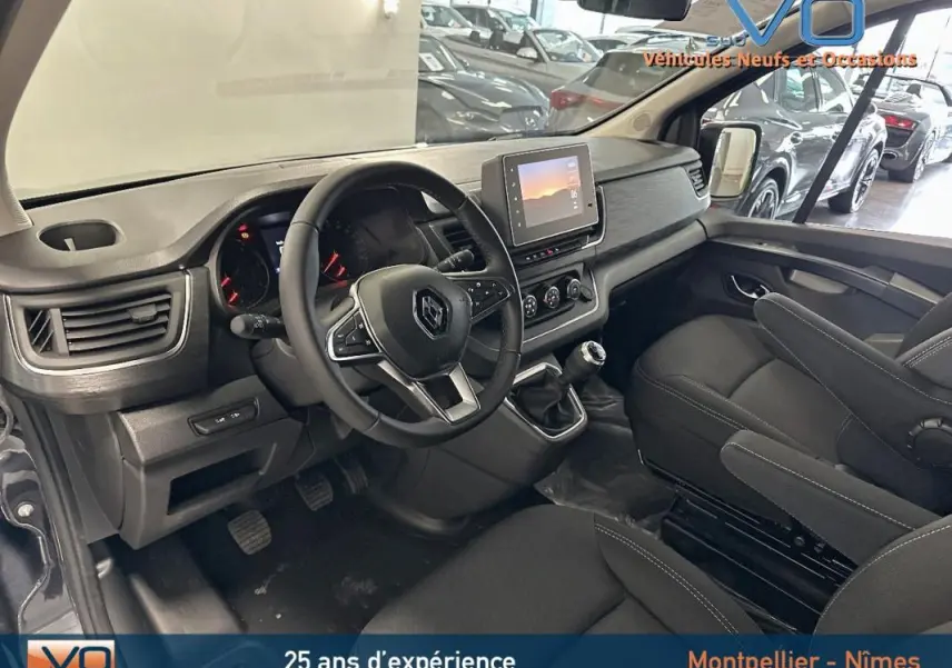 Intérieur du Renault Trafic Fourgon gris 2025, vue côté conducteur sur tableau de bord et sièges noirs.