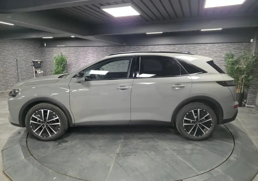 Vue latérale droite du DS7 Crossback gris métallisé 2025 avec jantes alliage noires et toit noir brillant.