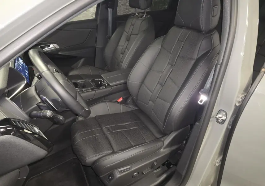 Vue intérieure côté conducteur du DS7 Crossback gris, sièges avant en cuir noir avec surpiqûres et console centrale visible.