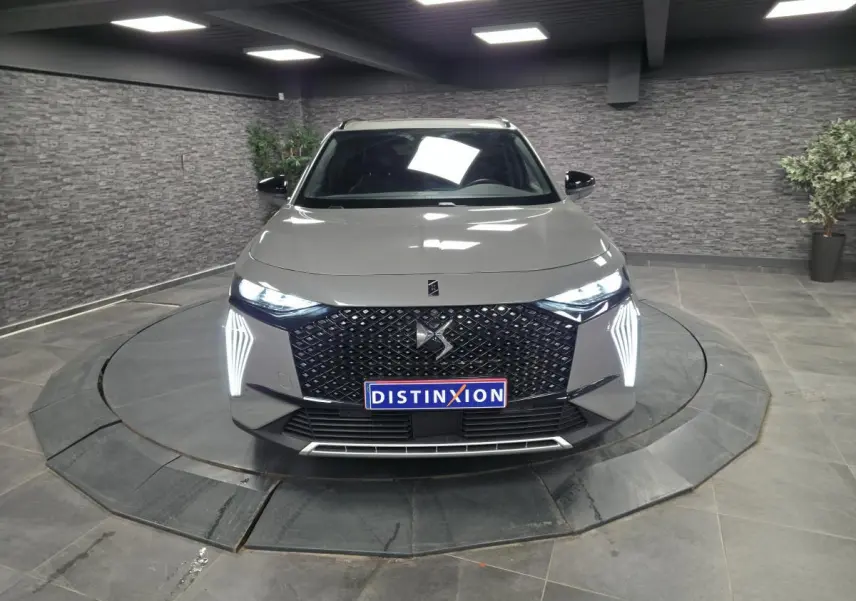 Vue de face du DS7 Crossback gris avec calandre noire à motif diamant et feux LED verticaux allumés.