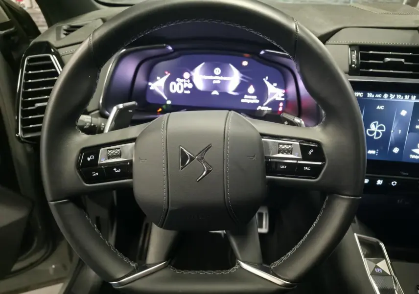 Vue rapprochée du volant en cuir noir du DS7 Crossback 2025 avec commandes intégrées et tableau de bord numérique.