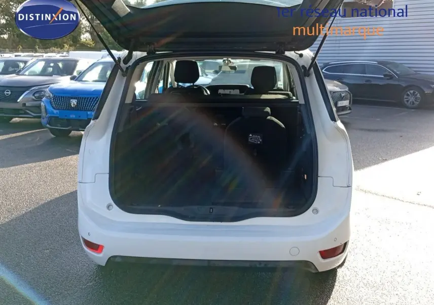 Vue arrière d'un Citroën Grand C4 Picasso blanc 2016 avec coffre ouvert et sièges rabattables visibles.