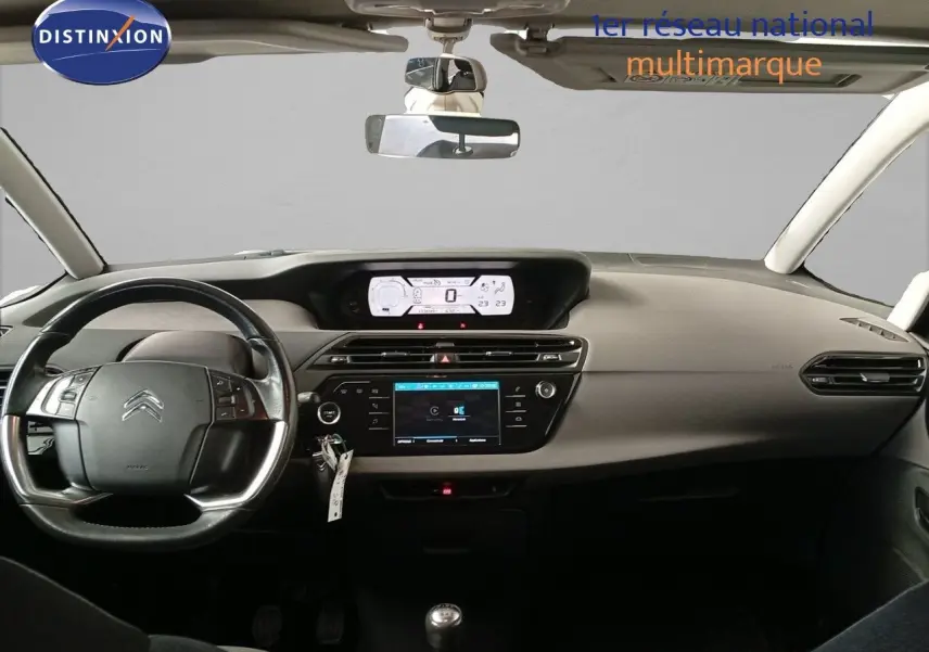 Tableau de bord et volant noir d'une Citroën Grand C4 Picasso blanc, vue frontale intérieure avec écran digital et boîte manuelle.