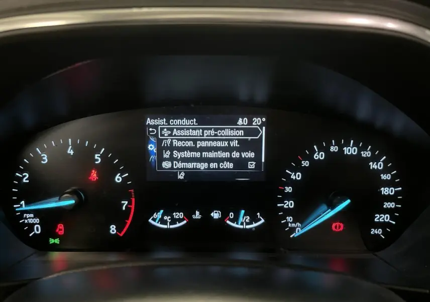 Tableau de bord de Ford Focus gris 2021 montrant l'écran d'assistance à la conduite et compteurs analogiques.