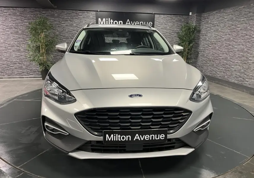 Vue avant d'une Ford Focus gris lunaire avec calandre noire et feux LED dans un showroom.