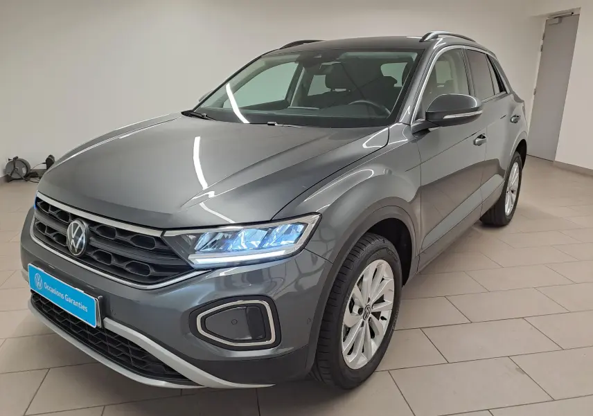 Volkswagen T-Roc 1.5 TSI gris Indium en vue 3/4 avant droit avec jantes alliage 17'' Johannesburg et phares allumés.