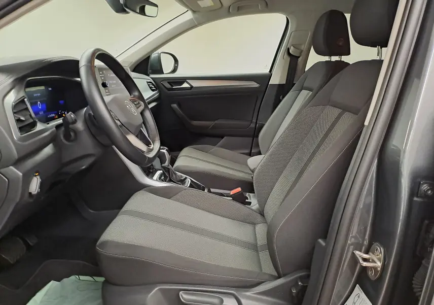Vue intérieure côté conducteur du Volkswagen T-Roc 2024 gris Indium, sièges tissu et tableau de bord moderne.