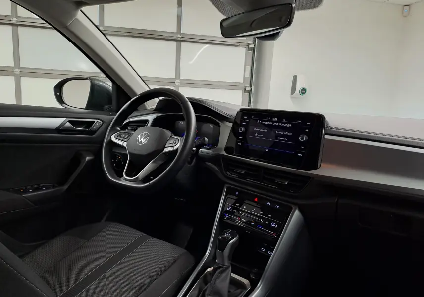 Vue intérieure côté conducteur du Volkswagen T-Roc 2024, avec tableau de bord moderne et écran tactile central.