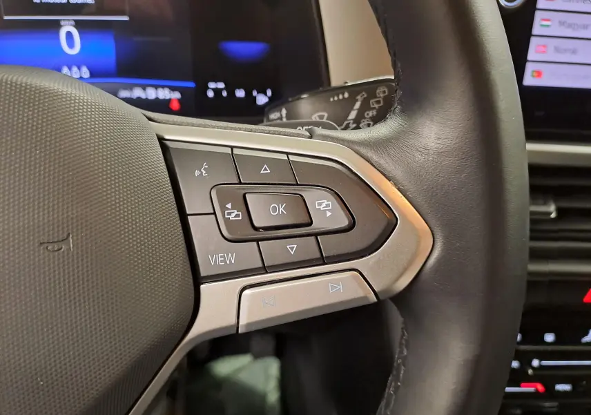 Gros plan sur les commandes à droite du volant cuir du Volkswagen T-Roc 2024, avec écran digital en arrière-plan.