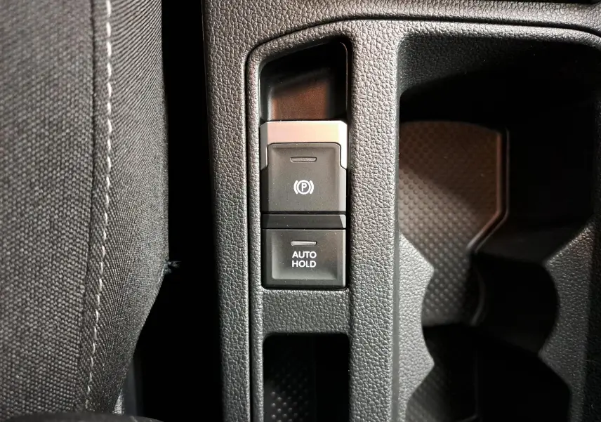 Boutons du frein de stationnement électronique et fonction Auto Hold sur la console centrale du Volkswagen T-Roc Gris Indium 2024.