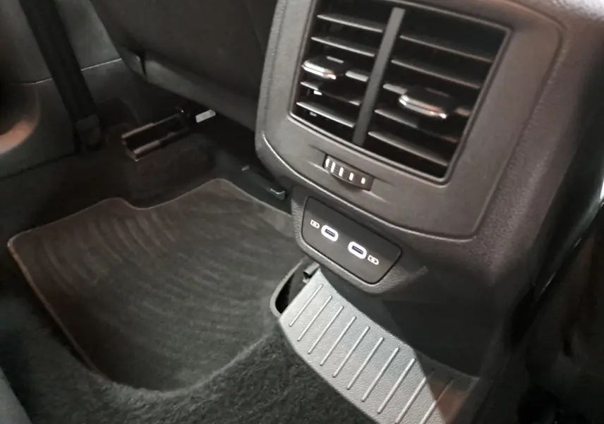 Prise de vue rapprochée de la console arrière noire du Volkswagen T-Roc 2024 avec deux ports USB-C et aérateurs.