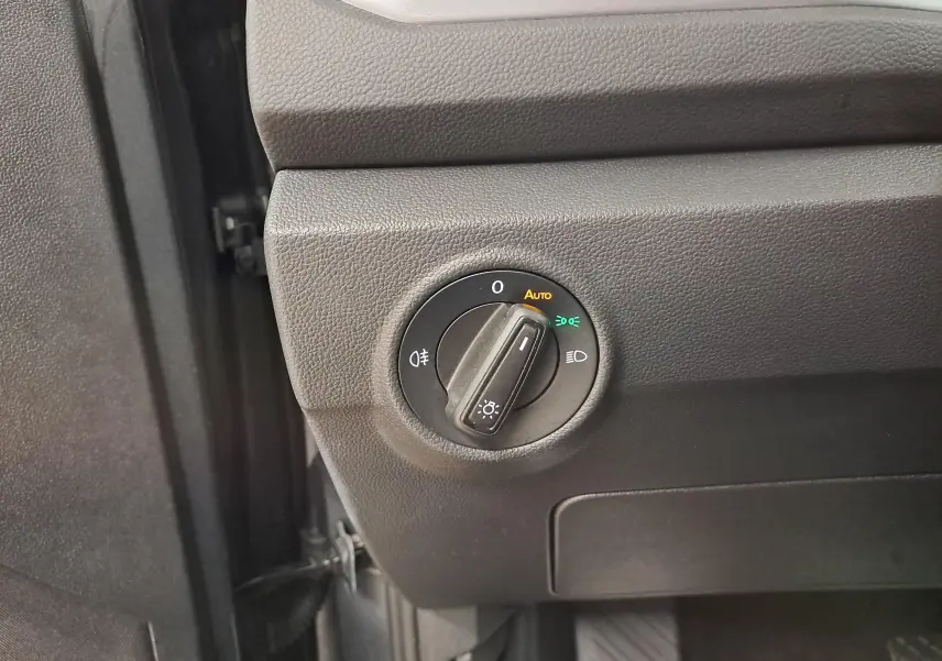 Gros plan sur le bouton de commande des phares du Volkswagen T-Roc 2024, intérieur noir texturé.