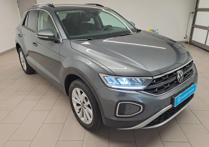 Volkswagen T-Roc gris Indium en 3/4 avant droit, avec jantes alliage 17'' Johannesburg et phares allumés.