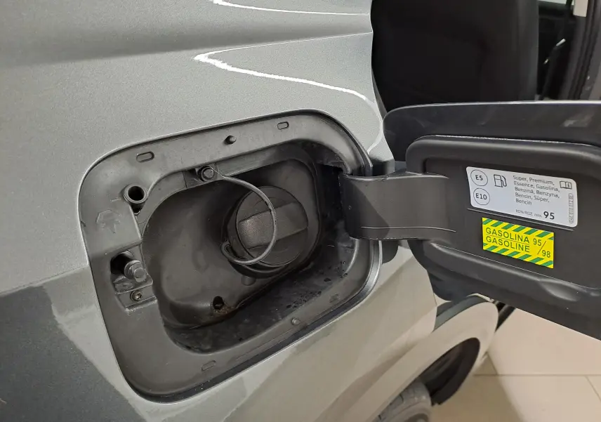 Gros plan sur la trappe à carburant côté gauche d’un Volkswagen T-Roc gris Indium 2024 avec bouchon essence ouvert.