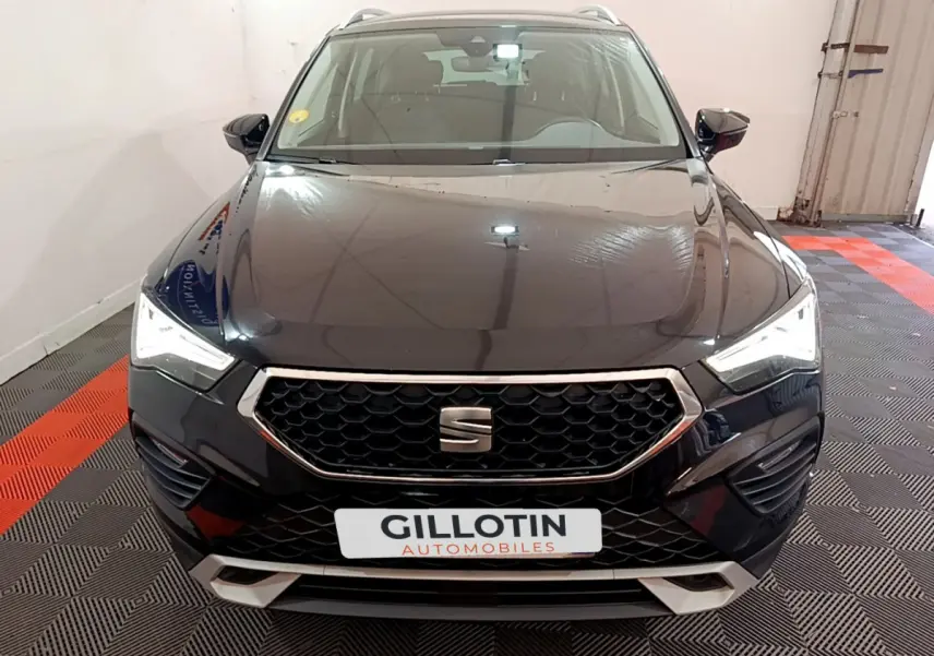 Vue de face d'un SEAT Ateca noir 2022 avec calandre hexagonale et phares LED allumés dans un garage.