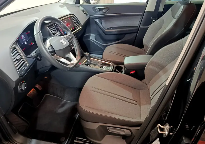 Intérieur avant droit du SEAT Ateca 2022 noir, avec sièges tissu gris, volant multifonctions et écran tactile central.