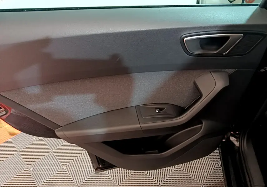 Intérieur côté gauche de la porte avant noire du SEAT Ateca 2022, avec poignée argentée et tissu gris.