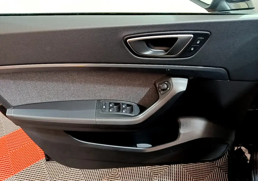 Intérieur côté gauche de la porte SEAT Ateca 2022 noire, avec commandes vitres et poignée argentée.