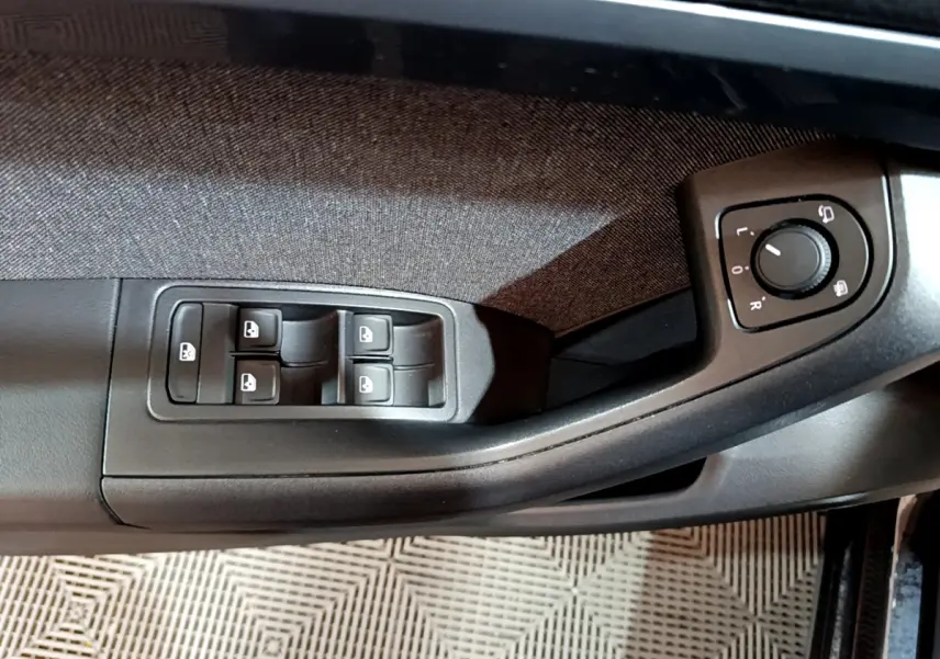 Vue rapprochée des commandes de lève-vitres et réglage des rétroviseurs côté conducteur d’un SEAT Ateca noir 2022.