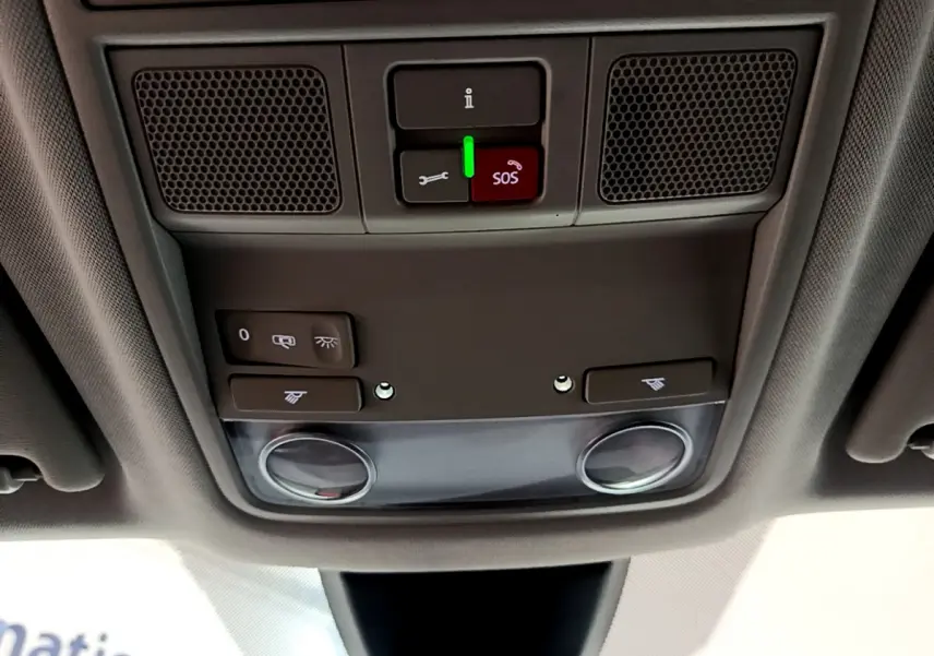 Vue en contre-plongée du panneau de commande au plafond intérieur du SEAT Ateca noir, avec bouton SOS rouge et éclairage intégré.
