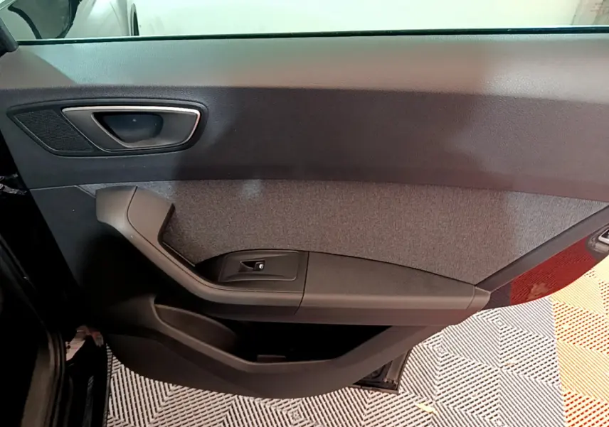 Vue intérieure du panneau de porte côté gauche du SEAT Ateca noir, avec poignée et commande de lève-vitre intégrée.