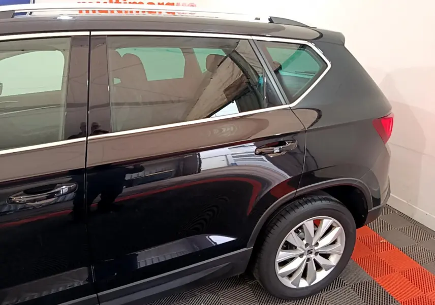 Profil arrière droit d'un SUV SEAT Ateca noir brillant avec jante alliage et poignées de porte chromées.