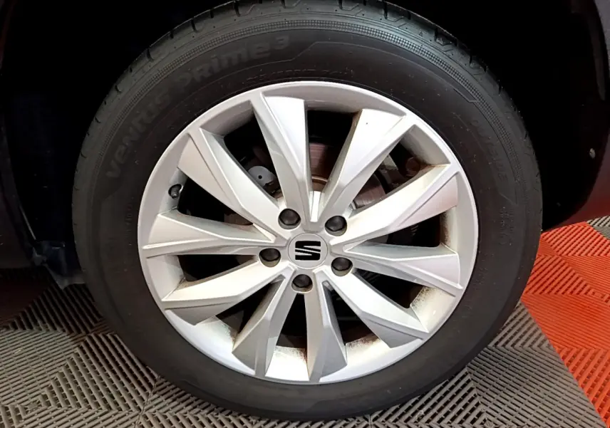 Gros plan sur la jante argentée du côté avant droit d'un SEAT Ateca noir, mettant en valeur le logo central SEAT.