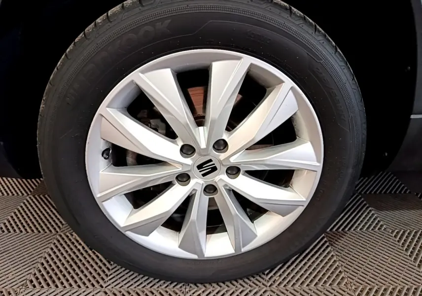 Gros plan sur la roue avant droite en alliage argenté du SEAT Ateca noir, mettant en valeur le logo central.