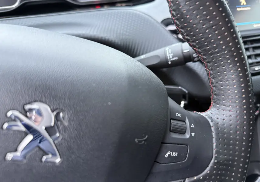 Gros plan sur le volant en cuir perforé avec surpiqûres rouges du Peugeot 2008 noir, version GT Line 2018.