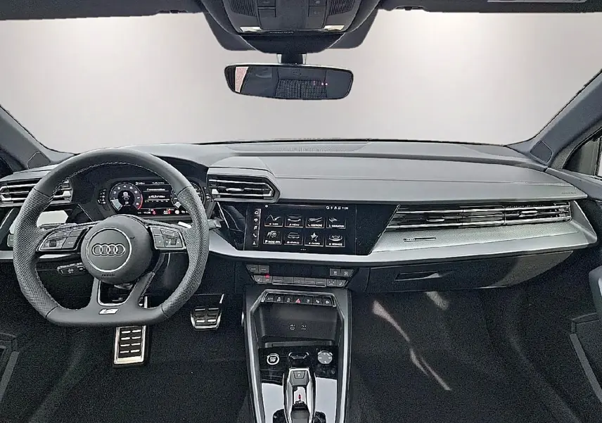 Vue intérieure avant de l'Audi A3 Sportback 2026 avec tableau de bord noir, volant sport multifonction et écran tactile central.