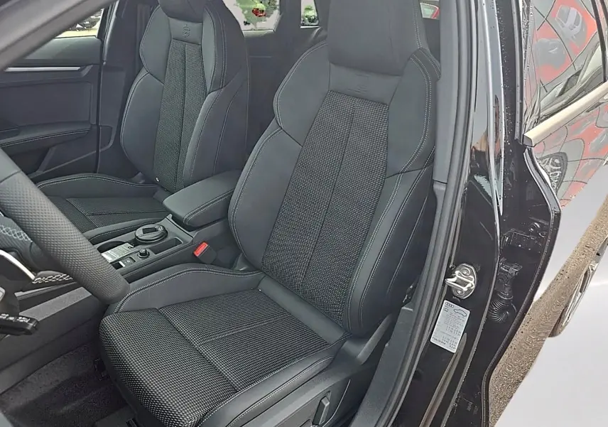 Vue intérieure côté conducteur de l'Audi A3 Sportback 2026 noir mythos, avec sièges sport et volant cuir multifonction.
