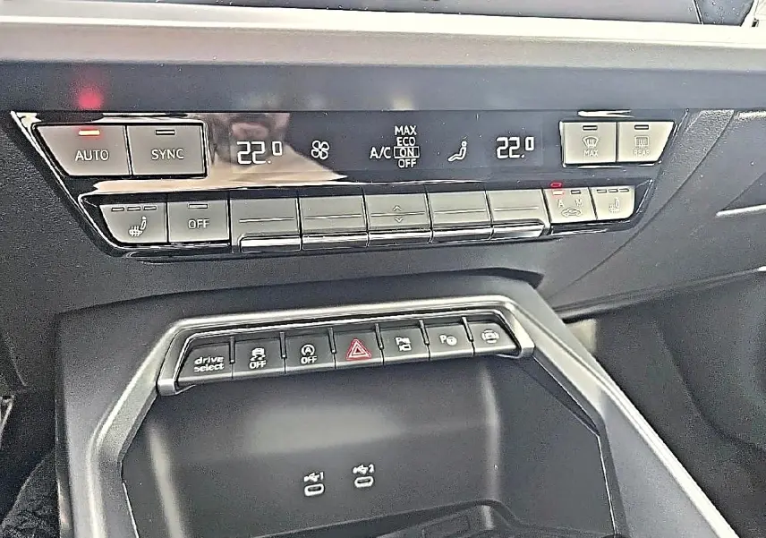 Vue rapprochée de la console centrale noire de l'Audi A3 Sportback 2026 avec commandes climatisation et boutons multifonctions.