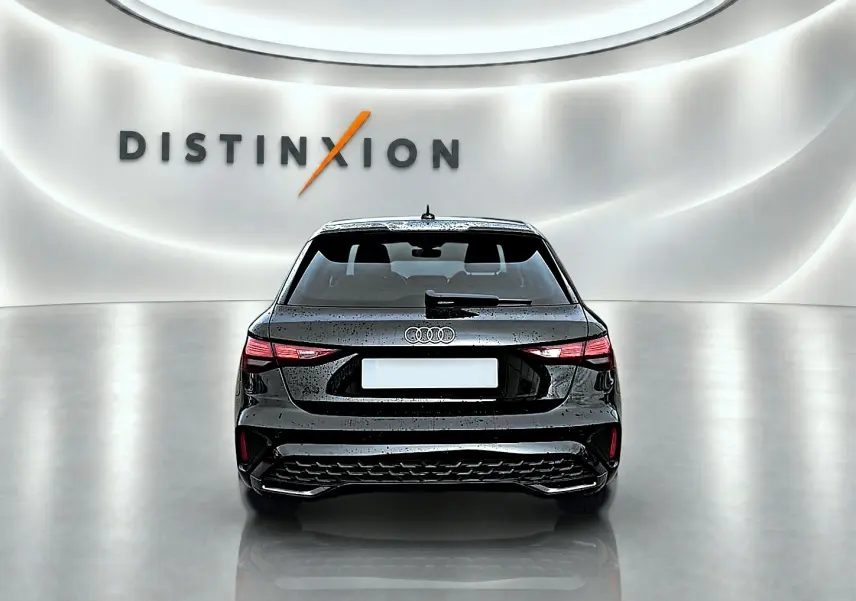 Vue arrière d'une Audi A3 Sportback 1.5 TFSI noire Mythos avec feux LED et becquet arrière dans un studio lumineux.