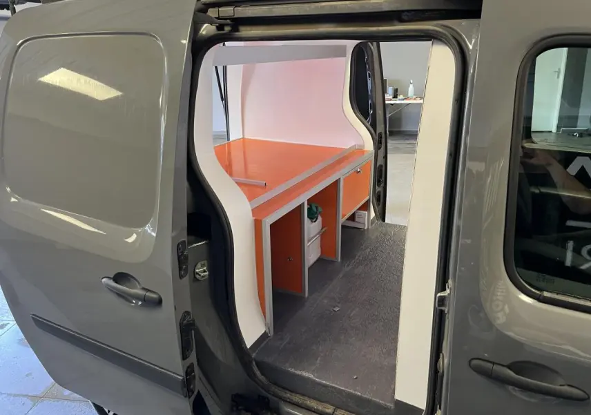 Vue côté gauche du Renault Kangoo Express gris foncé avec porte coulissante ouverte et aménagement intérieur orange visible