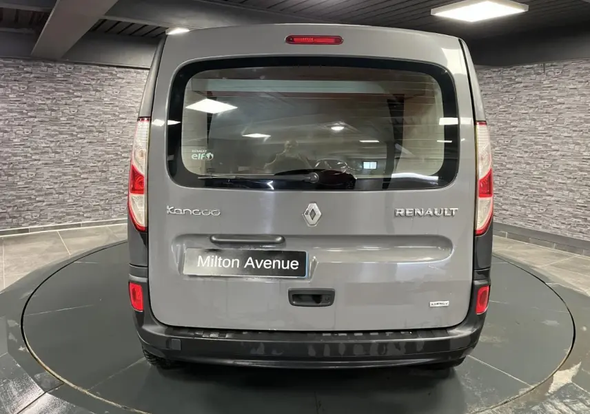 Vue arrière d'un Renault Kangoo Express gris foncé avec hayon vitré et pare-chocs noir grainé dans un showroom.