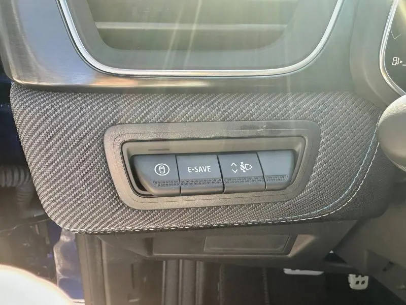 Gros plan sur les commandes E-SAVE et réglage des phares sur la planche de bord en textile noir du Renault Captur rouge flamme.