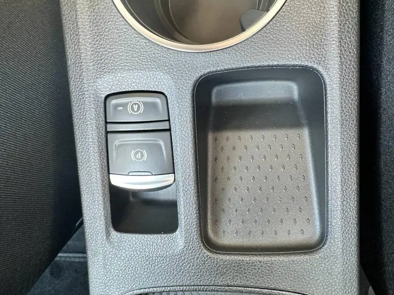 Gros plan sur la console centrale noire du Renault Captur 2025 avec commandes frein à main électrique et rangement adjacent.