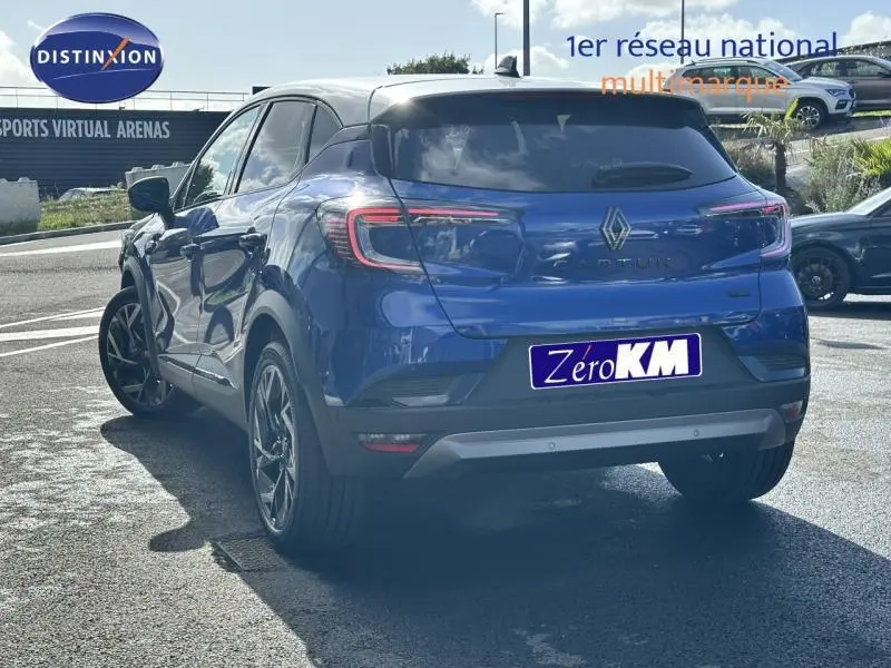 Vue 3/4 arrière droite d'un Renault Captur 2025 bleu Rouge Flamme avec jantes alu et feux arrière LED distinctifs.