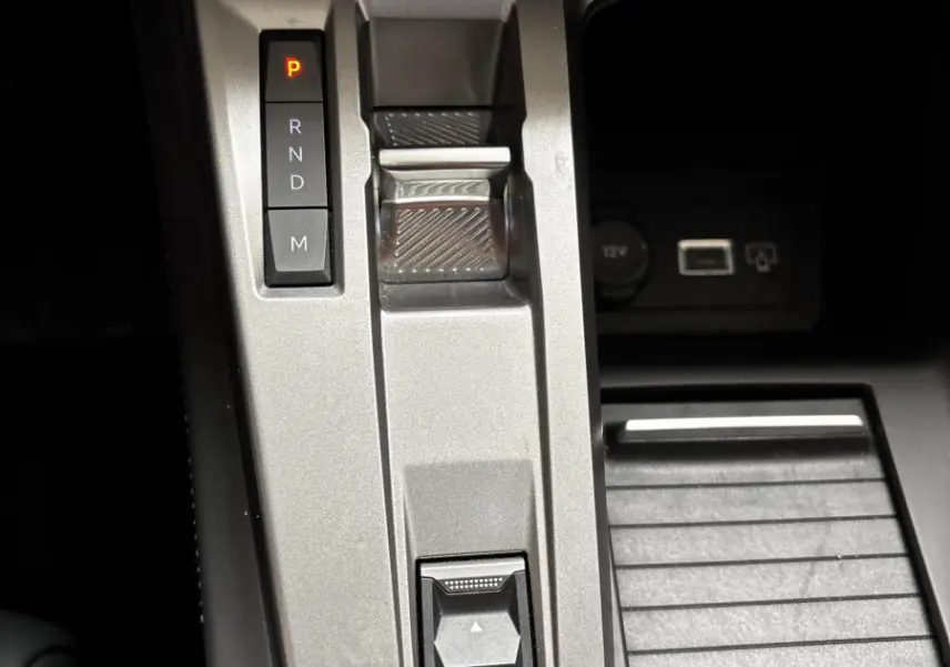 Gros plan sur la console centrale grise de la Peugeot 308 2024 avec bouton start/stop et sélecteur Drive Mode.