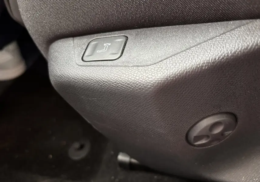 Bouton de réglage de siège en gros plan à l'avant droit d'un Peugeot 308 gris clair 2024.