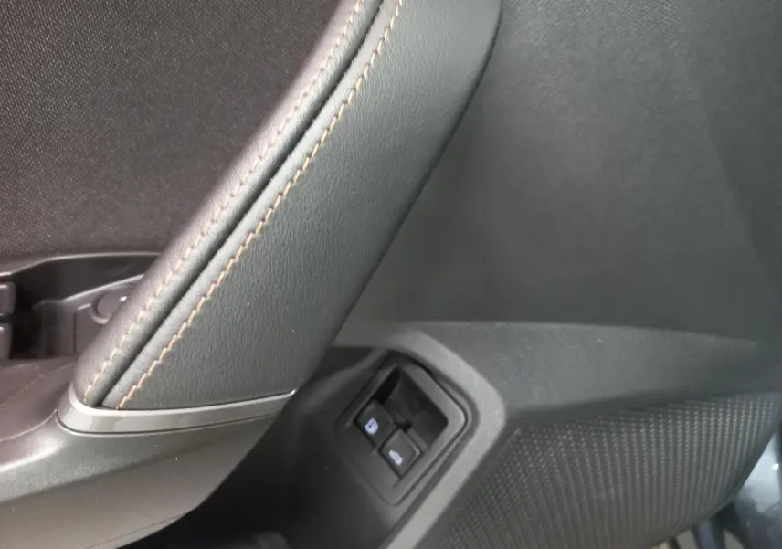 Détail de la commande des vitres côté gauche avec surpiqûres marron sur le revêtement intérieur noir du CUPRA Formentor gris magnétique.