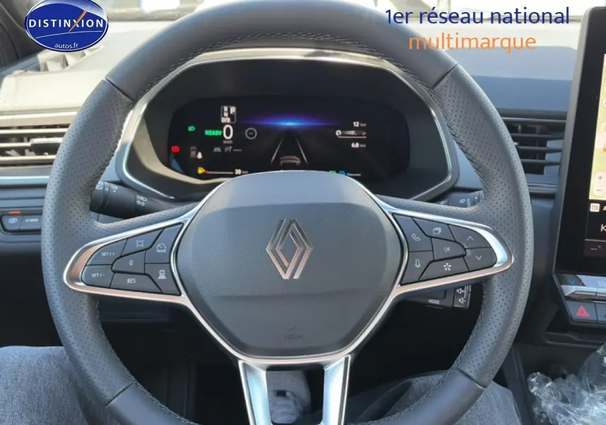 Vue rapprochée du volant multifonction noir avec logo Renault et tableau de bord numérique du Captur hybride 2026.