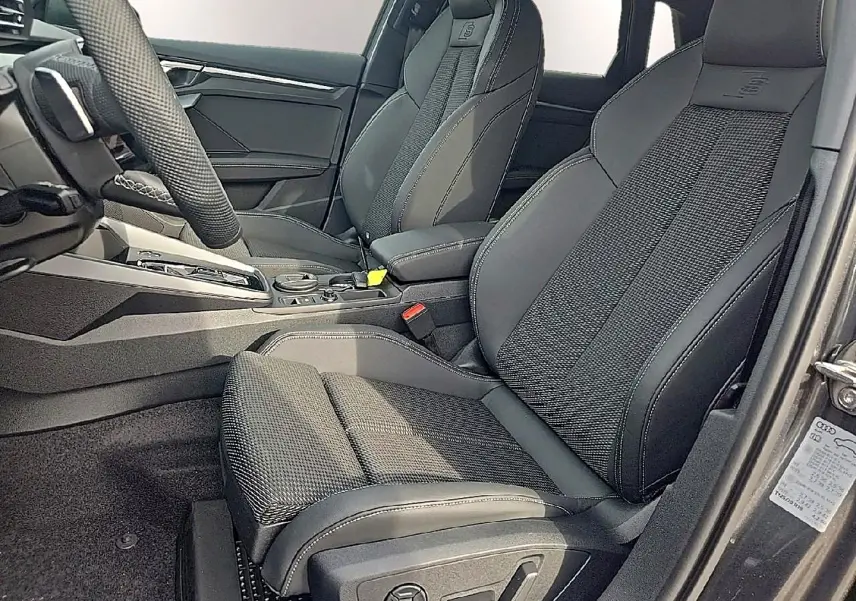 Vue intérieure côté conducteur de l'Audi A3 Sportback 2026 avec sièges sport noirs et surpiqûres grises S line.
