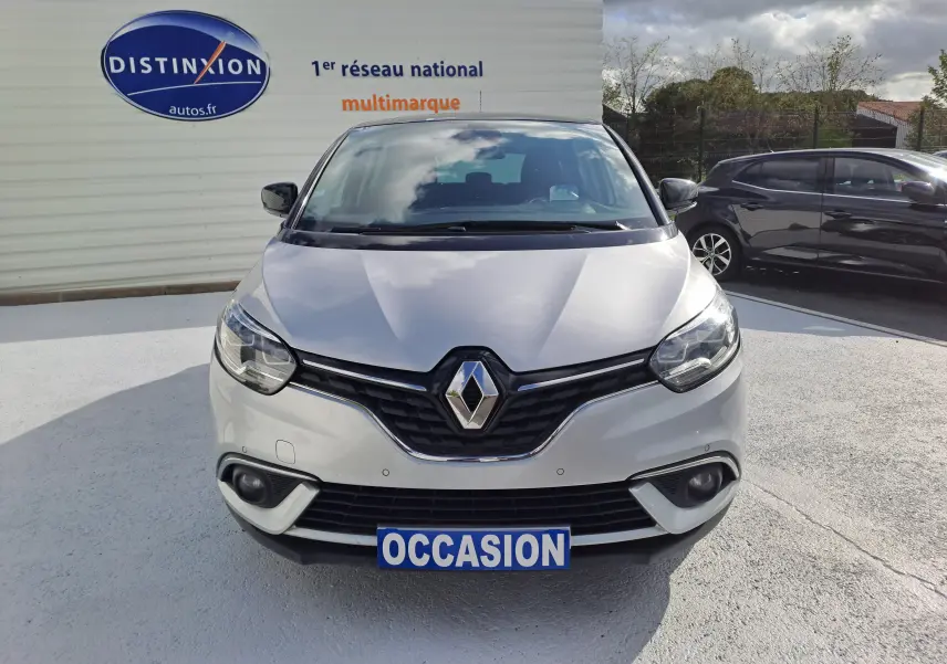 Vue de face d'un Renault Scenic IV gris platine avec toit noir, affichant une plaque "OCCASION" sur un parking extérieur.