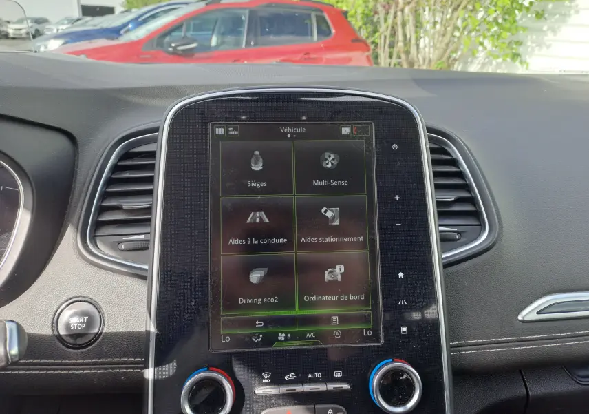 Vue intérieure du tableau de bord du Renault Scenic IV 2018 avec écran tactile central et commandes de climatisation visibles.