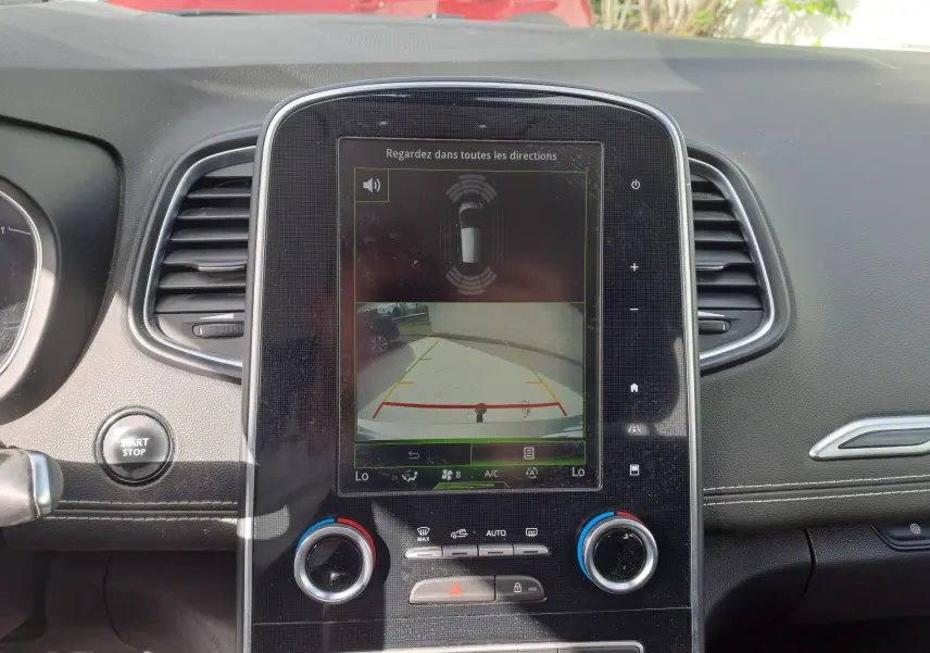 Écran central tactile affichant la caméra de recul et les capteurs de proximité dans le tableau de bord noir du Renault Scenic IV.