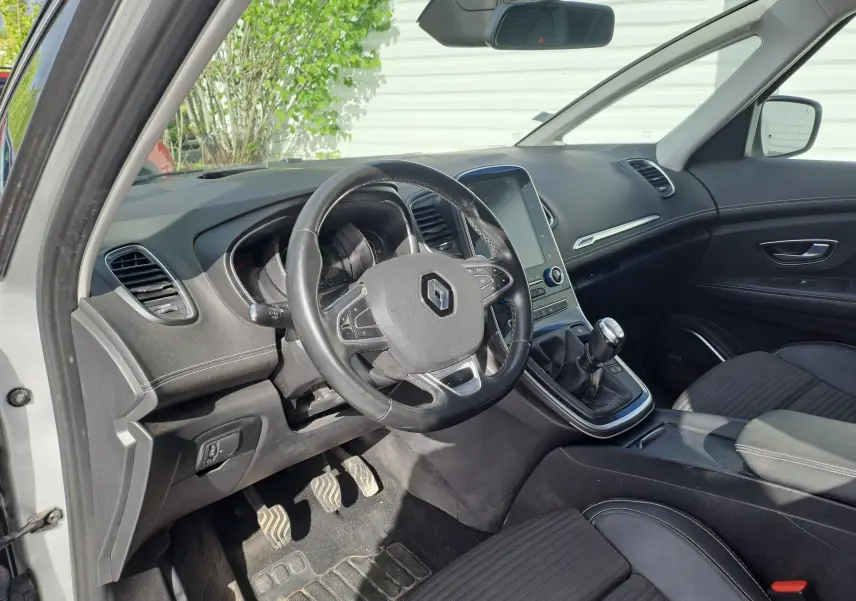 Intérieur avant gauche du Renault Scénic IV gris platine, volant cuir, tableau de bord moderne avec écran tactile vertical.