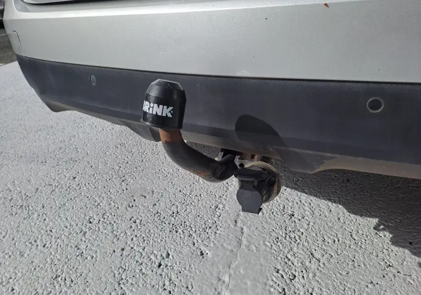 Vue rapprochée de l'attelage de remorque noir fixé au pare-chocs arrière gris platine d'un Renault Scenic IV 2018.